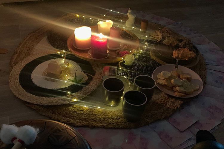 Cercle de bougies et de guirlandes lumineuses posé sur un tapis tressé