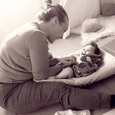 Une maman penchée sur son bébé allongé sur un tapis, photo en noir et blanc