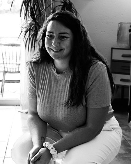 Portrait de Priscilla, assise, souriante, en noir et blanc
