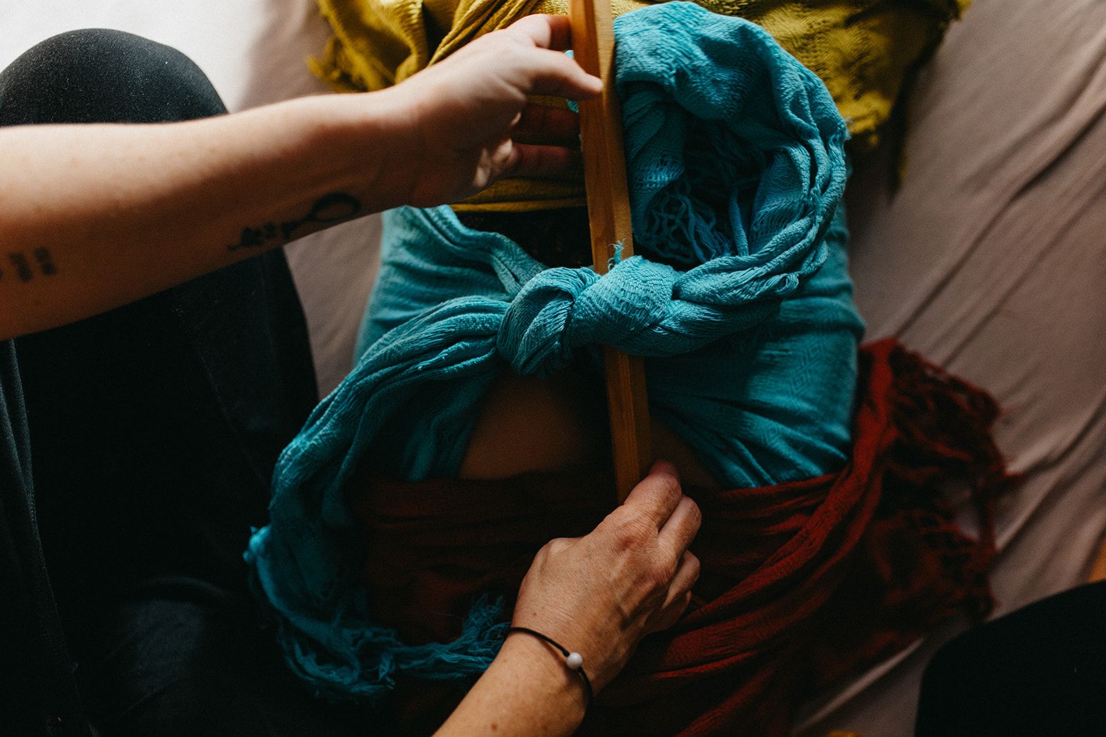 Un foulard turquoise noué sur le ventre d'une femme pendant le serrage du corps