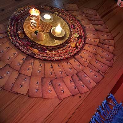 Un cercle de bougies posé sur un tapis tressé, entouré de cartes