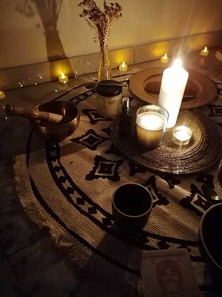 Bougies, bol chantant et tapis posés dans une lumière chaude