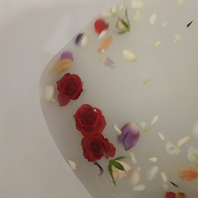 Des pétales de fleurs et des roses rouges flottent dans un bain
